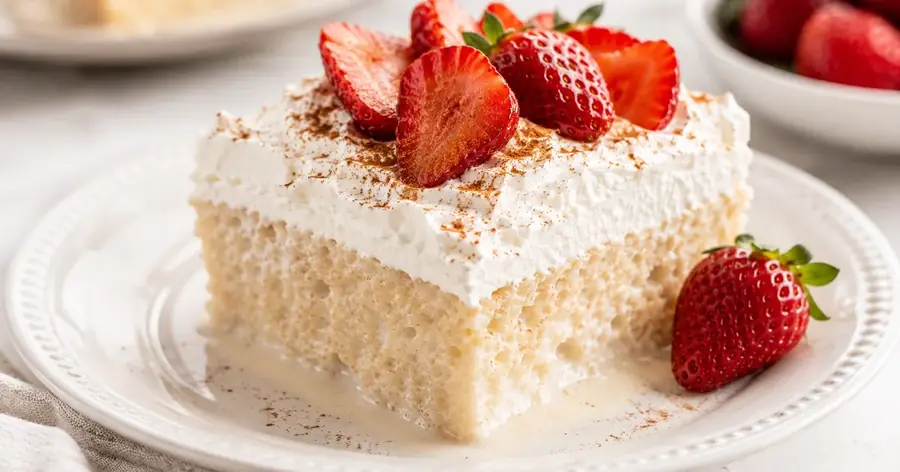 Tarta tres leches con cobertura de nata y fresas sobre fondo blanco | Academia Dulce