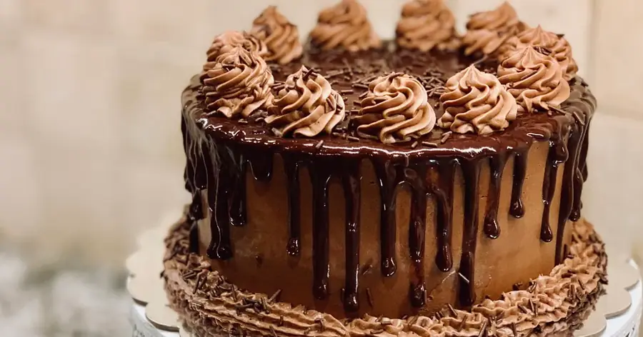 Tarta de chocolate con decoración profesional de ganache y rosetones de crema sobre base de cartón